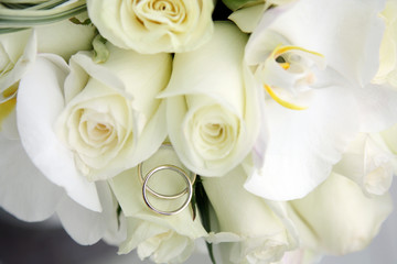background of beautiful wedding bouquet of roses and orchids and two gold and platinum wedding rings