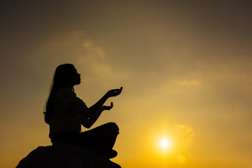 Plakat Prayer. Silhouette girl prays at sunset.