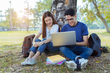 Students young asian together using laptop computer consult and reading book study smiling at university high school campus,college in summer holiday relaxation