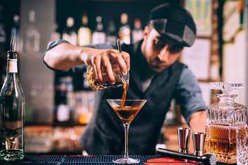 Barman creating signature drink at bar counter. Bitter whisey with beer cocktail - obrazy, fototapety, plakaty
