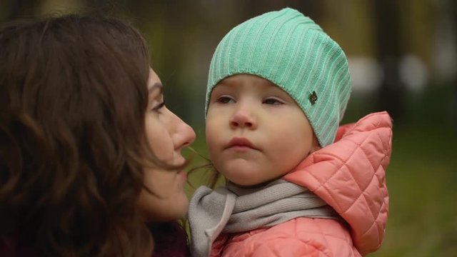 Portrait of beautiful young woman with a child in an autumn park. Portrait of two, young mother and daughter. slow-motion