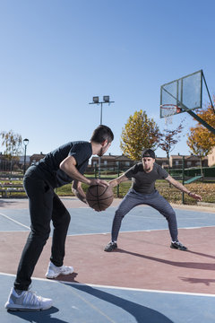 Men playing basketball on sunny day