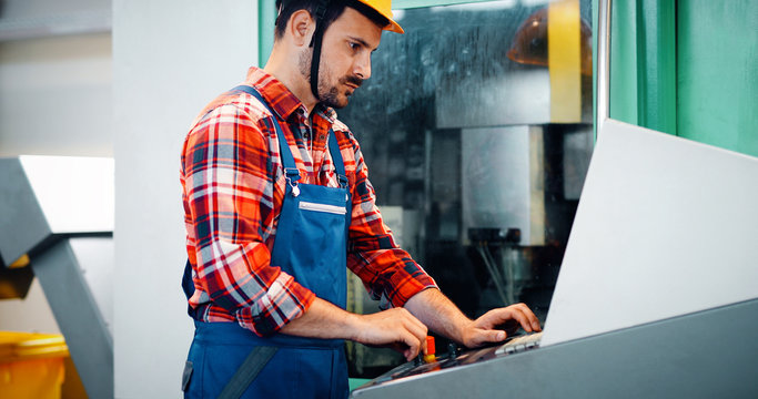 Industry Worker entering data in CNC machine at factory