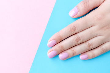 Close up pink nails for girls. Stylish trendy female manicured fingernails. Beautiful young woman's hands on pink and blue background. Top view, flat lay. copy space for text