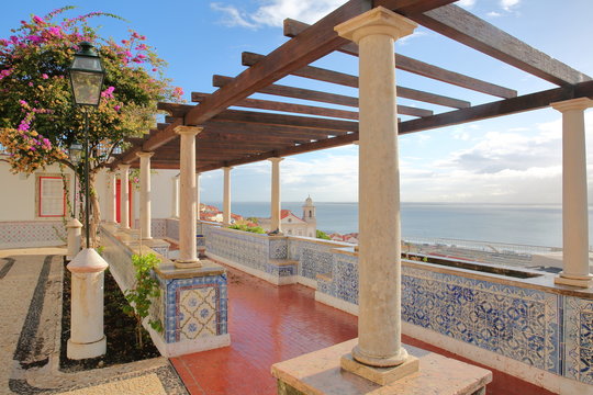 Santa Luzia viewpoint (miradouro) with columns and tiles in the foreground and Santa Estevao Church and Tagus river in the background, Lisbon, Portugal