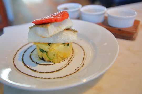 Cod fillet (Bacalhau), traditional Portuguese dish with potatoes and spinach puree, olive oil and dried tomato, Lisbon, Portugal