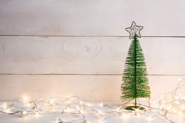 Metal green christmas tree with garland on wooden background