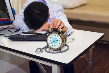 Alarm clock with overwork doctor after operation case , Stressed medical clock in front has tried and headache out of time pressure.