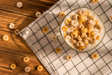 top view cup of milk with cereal rings in a sunny morning as healthy breakfast