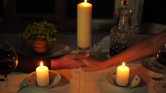 Close up Of Man's Hand Takes The Woman's Hand Over The Table Candles