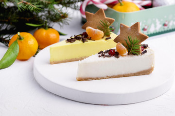 Christmas Dessert Two Slice of Cheesecakes Decorated with Citrus Gingerbread Star and Berries WoodenTray White Background Fir Branches Citrus