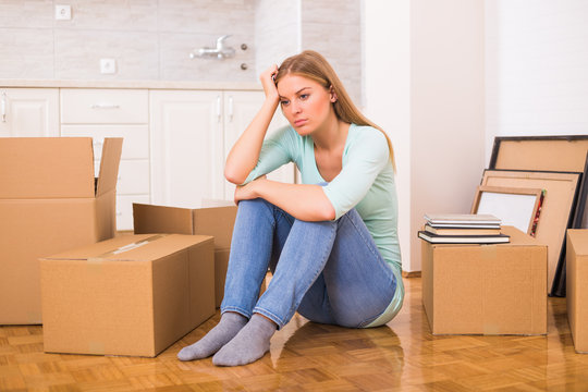 Tired woman sitting on the floor while moving into new home.
