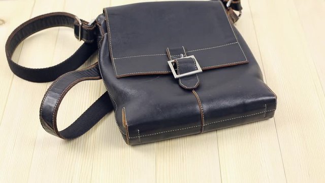 Leather goods for men. The man came home and lays down his leather accessories on a wooden table, a bag, a key case, a parole wallet, gloves, a watch