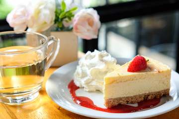 Strawberry cheese pie with fresh strawberry on top , there is vase of rose in the background in coffee shop in the morning time