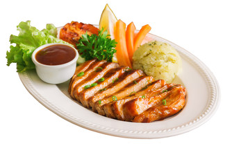 White isolated background with clipping paths homemade pork steak or barbecue slices on white plate served with mash potato, barbecue sauce and vegetable. Delicious food for lunch or dinner.