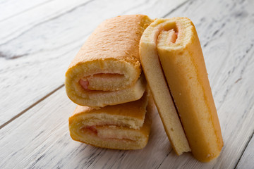 three  strawberry flavor sweet rolls on white wood