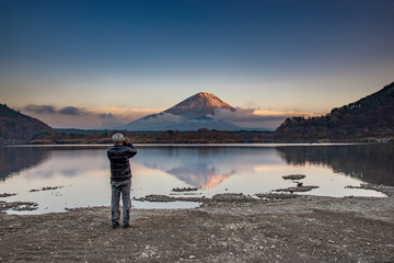 A man take photo on mountain Fuji at Kawaguchiko lake in japan with blue cloud sky