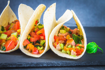 Traditional Mexican tacos with meat and vegetables on wooden background.