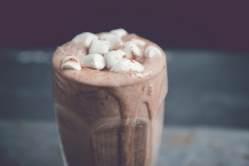 Hot chocolate with marshmallow on the wooden background. Shallow depth of field. Toned image.