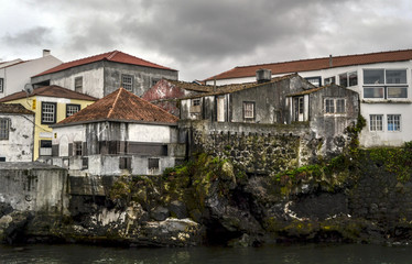 Fototapeta na wymiar old houses on rocks with red roofs in the port of the island of Pico in the Azores
