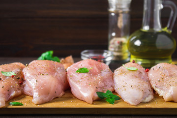 Raw chicken fillets on a cutting board against the background of a wooden table. Meat ingredients for cooking.