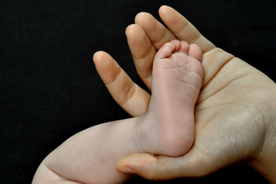 motherhand and baby foot isolated on a black background