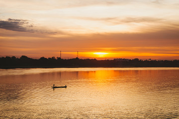 Fototapeta premium Fisherman floats on a lake at sunrise.