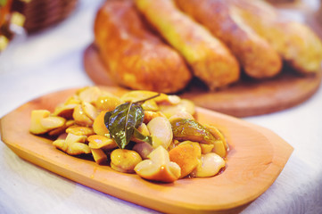Marinated mushrooms on the board. Against the background of the festive table. Warm toning