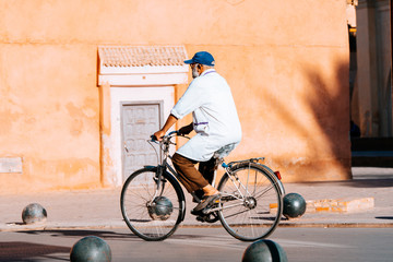 old man riding a bike inside marrakech medina, morocco