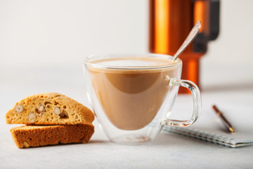Coffee of a cappuccino, biscotti and notebook  on a table. Selective focus