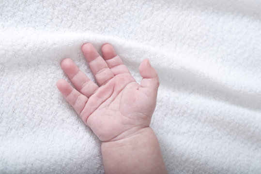 Beautiful baby hand on white soft blanket