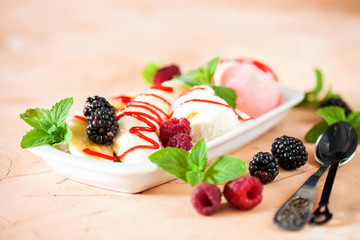 Summer fruit berry breakfast. Healthy banana split breakfast with white and pink ice cream , raspberries, blackberries, mint. On white plate. Selective focus
