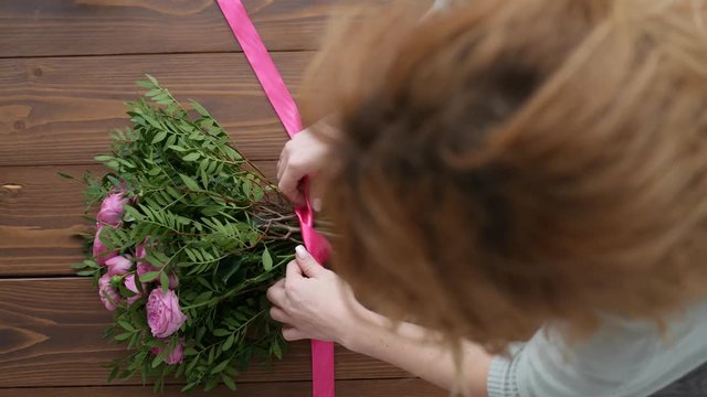 Top View of Female florist making beautiful bouquet at flower shop, peone and rose flower composition for wedding