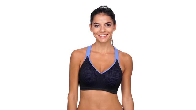 Happy brunette fitness woman showing thumbs up at camera over white background