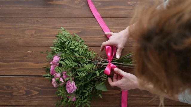Top View of Female florist making beautiful bouquet at flower shop, peone and rose flower composition for wedding