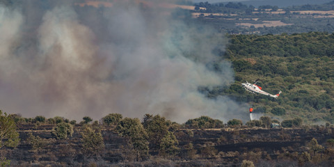 Fototapeta premium Fire in the wilderness with helicopter throwing water