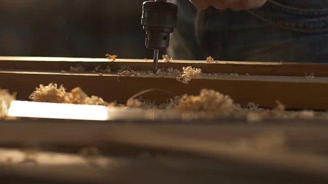 The carpenter uses a hand-held vintage drill in his work place. Slow motion