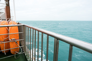 Side view of orange lifeboat steel fence and barrier to prevent passengers falling from boat.