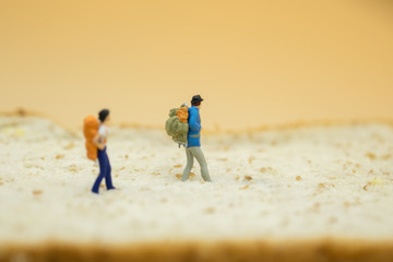 Food and Travel Concept. Male and female traveler miniature figures with backpack walking on top of whole wheat bread.
