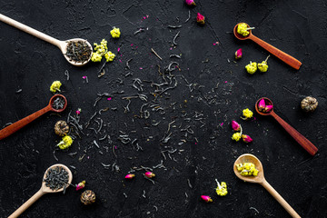 Aromatic tea. Wooden spoons with dried tea leaves, flowers and spices on black background top view copyspace