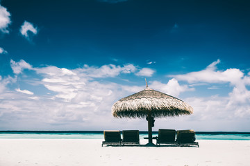 Straw umbrella and sunbeds on a sandy beach
