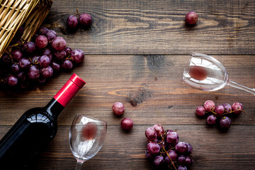Fototapeta na wymiar Drink wine. Bottle, glaas and grape on dark wooden background top view copyspace