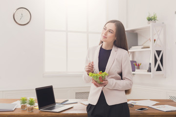 Young business woman eating salad at office