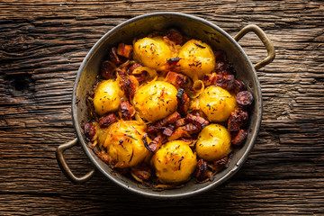 Potatoes. Roasted potatoes with bacon onion and sausages on old oak table