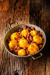 Potatoes. Roasted potatoes with bacon onion and sausages on old oak table