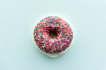 Pink donut with colorful sprinkles isolated on background
