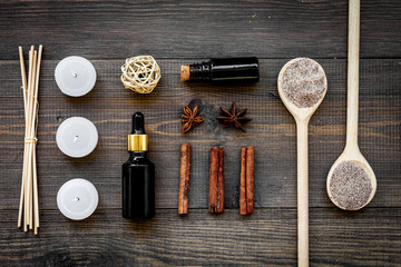 Fototapeta na wymiar Skin care and relax. Cosmetics and aromatherapy concept. Spa salt and oil with spices cinnamon on dark wooden background top view