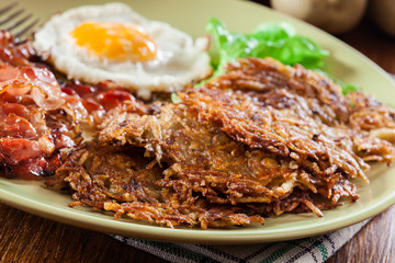 Hash browns. Potato pancakes with crispy fried bacon and fried egg