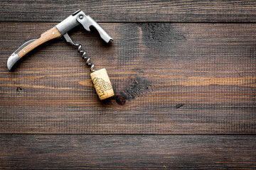 Open wine bottle. Corks and corkscrew on dark wooden background top view copyspace
