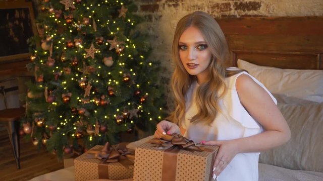Young beautiful girl wraps a Christmas gift
